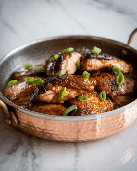 Maple Miso Glazed Chicken in a copper serving dish on a white surface
